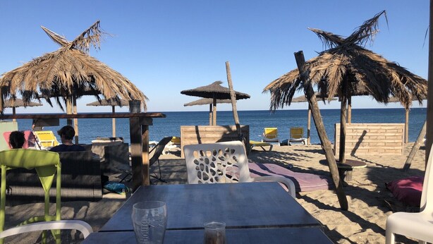 A beachside seating area with tables and chairs, thatched umbrellas, and a view of the sea. - typical small house, air-conditioned fisherman's farmhouse (swimming pool, jacuzzi, sauna, fitness room) (Le Barcarès)