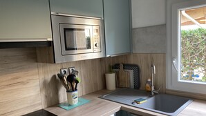 A modern kitchen with a built-in microwave, a sink, and wooden cabinetry. - typical small house, air-conditioned fisherman's farmhouse (swimming pool, jacuzzi, sauna, fitness room) (Le Barcarès)