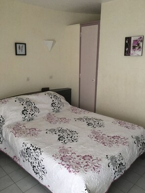Ein Schlafzimmer mit Bett, Kleiderschrank und Wandleuchte.