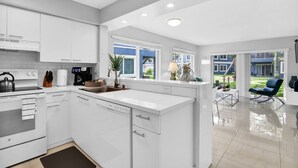 A modern kitchen with white cabinetry, a built-in oven, and a large island with a sink. - 340A - Boca Retreat w/ Pool, Parking, Near Evert Tennis & Shops (Boca Raton)