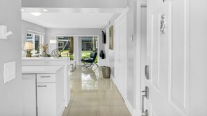 A modern kitchen with white cabinetry, a dining area with a table and chairs, and a view of a garden through glass doors. - 340A - Boca Retreat w/ Pool, Parking, Near Evert Tennis & Shops (Boca Raton)
