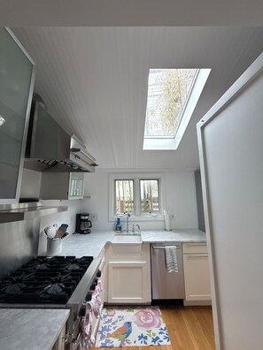 A kitchen with a skylight, a stove, a sink, and cabinets. - Nama-stay, sweet pink Saugatuck Shores beach cottage (Westport)