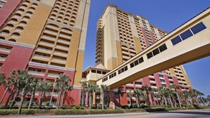A high-rise hotel with multiple balconies and a pedestrian bridge.