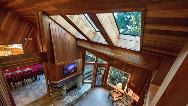 A cozy cabin interior with a stone fireplace, wooden ceiling, and a dining area. - Four Seasons (Yosemite)