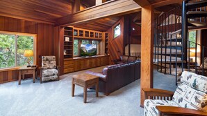 A spacious living room with a large leather sofa, wooden flooring, and a built-in TV. - Four Seasons (Yosemite)
