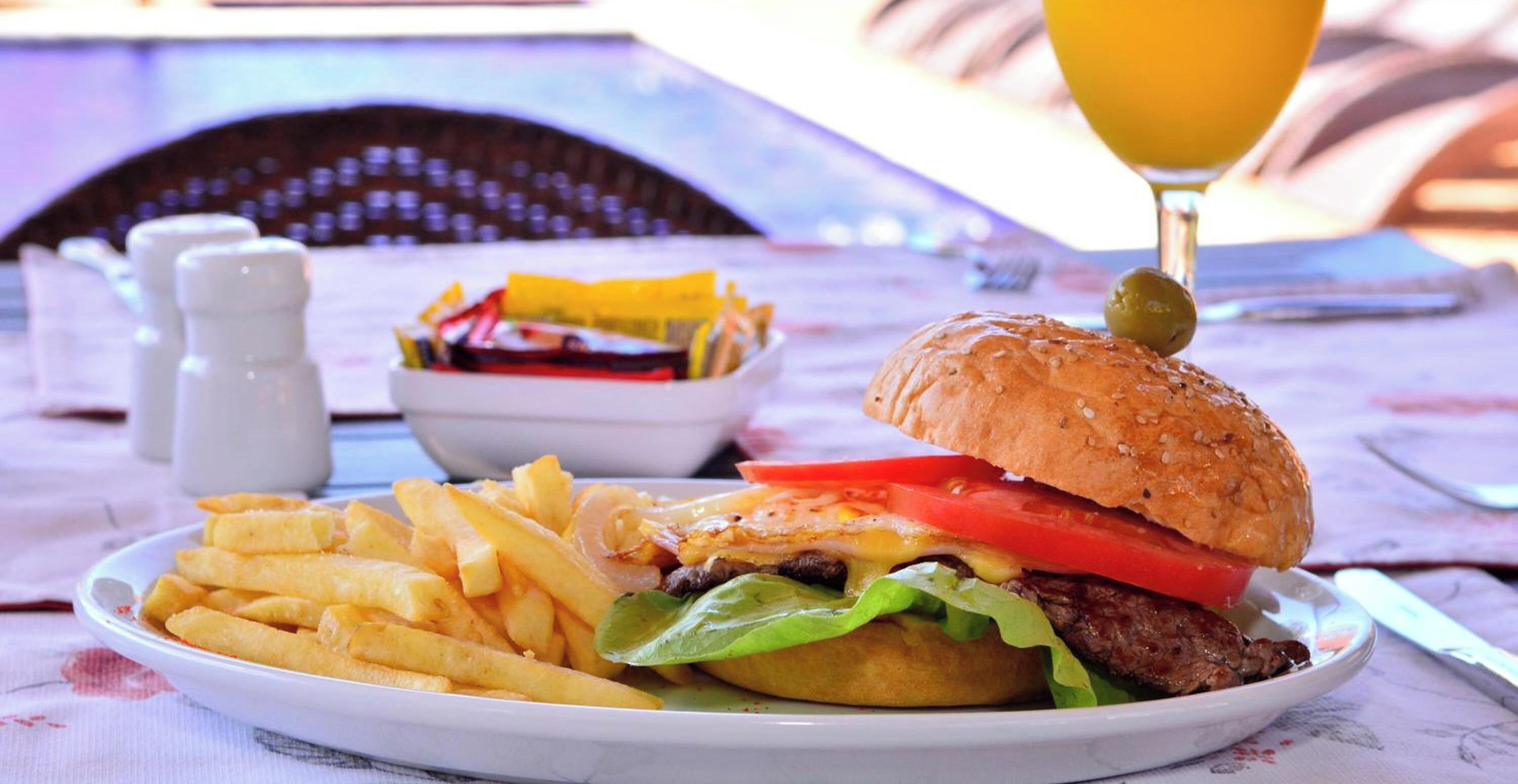 A meal consisting of a hamburger, fries, and a drink on a table.