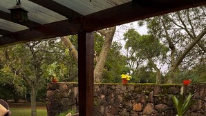 Una vasca idromassaggio in una zona esterna coperta, con un muro di pietra e vegetazione sullo sfondo.