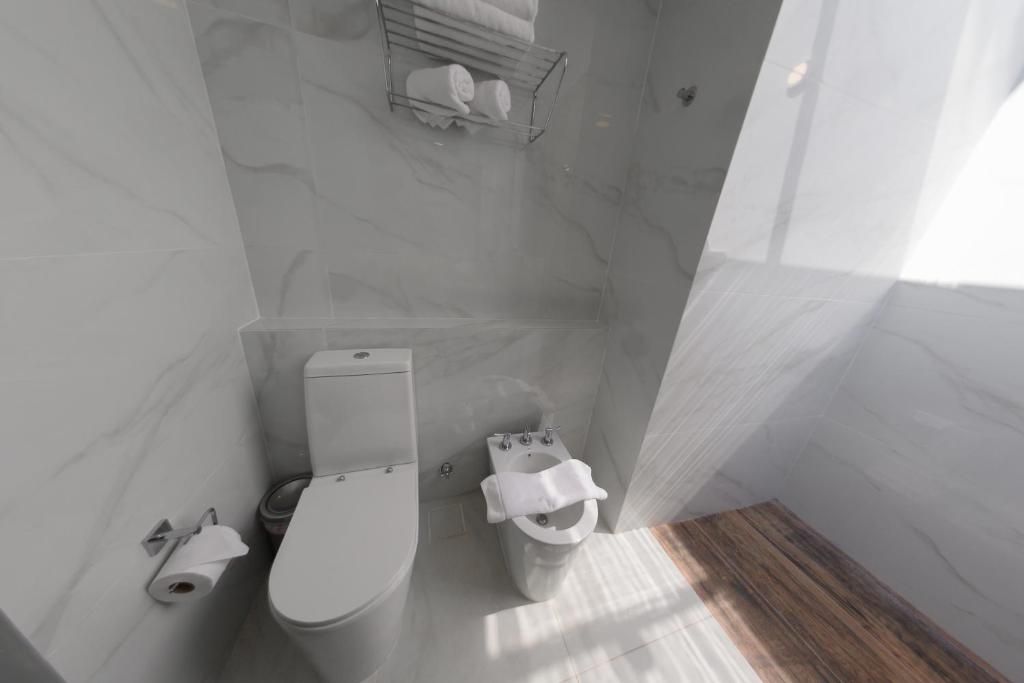 Un baño con inodoro, ducha y barra para toallas.