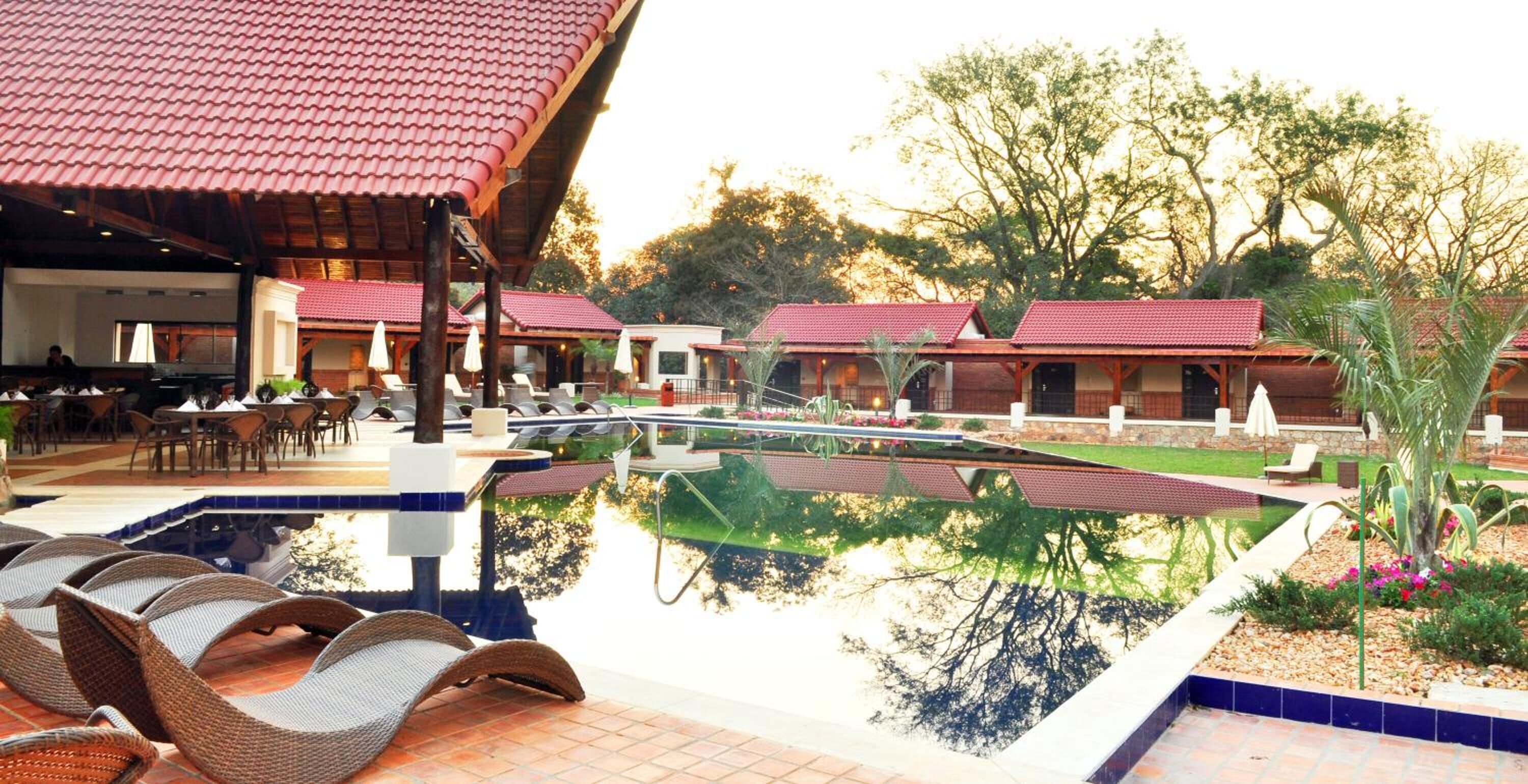 A pool area with lounge chairs, a covered seating area, and a reflection pool.