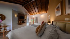 Un'ampia camera da letto con un grande letto, soffitto in legno, televisore a parete e una scrivania con sedia.