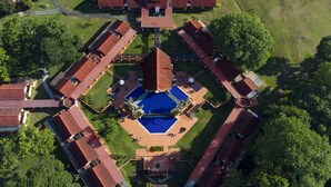 Una vista aerea di un resort con una piscina centrale circondata da diversi edifici con tetti rossi.
