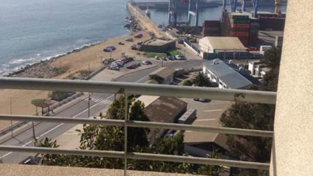 A view of a coastal area with a beach, parking lot, and industrial cranes.