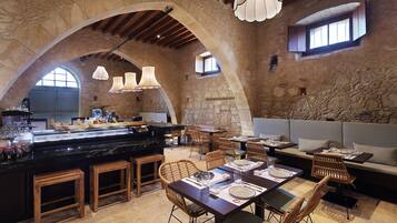 A rustic interior with stone walls, wooden furniture, and a bar area.