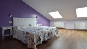 Een slaapkamer met een bed, nachtkastje, raam en een radiator.