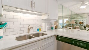 Une cuisine moderne avec des meubles blancs, un évier à deux bacs et un lave-vaisselle.