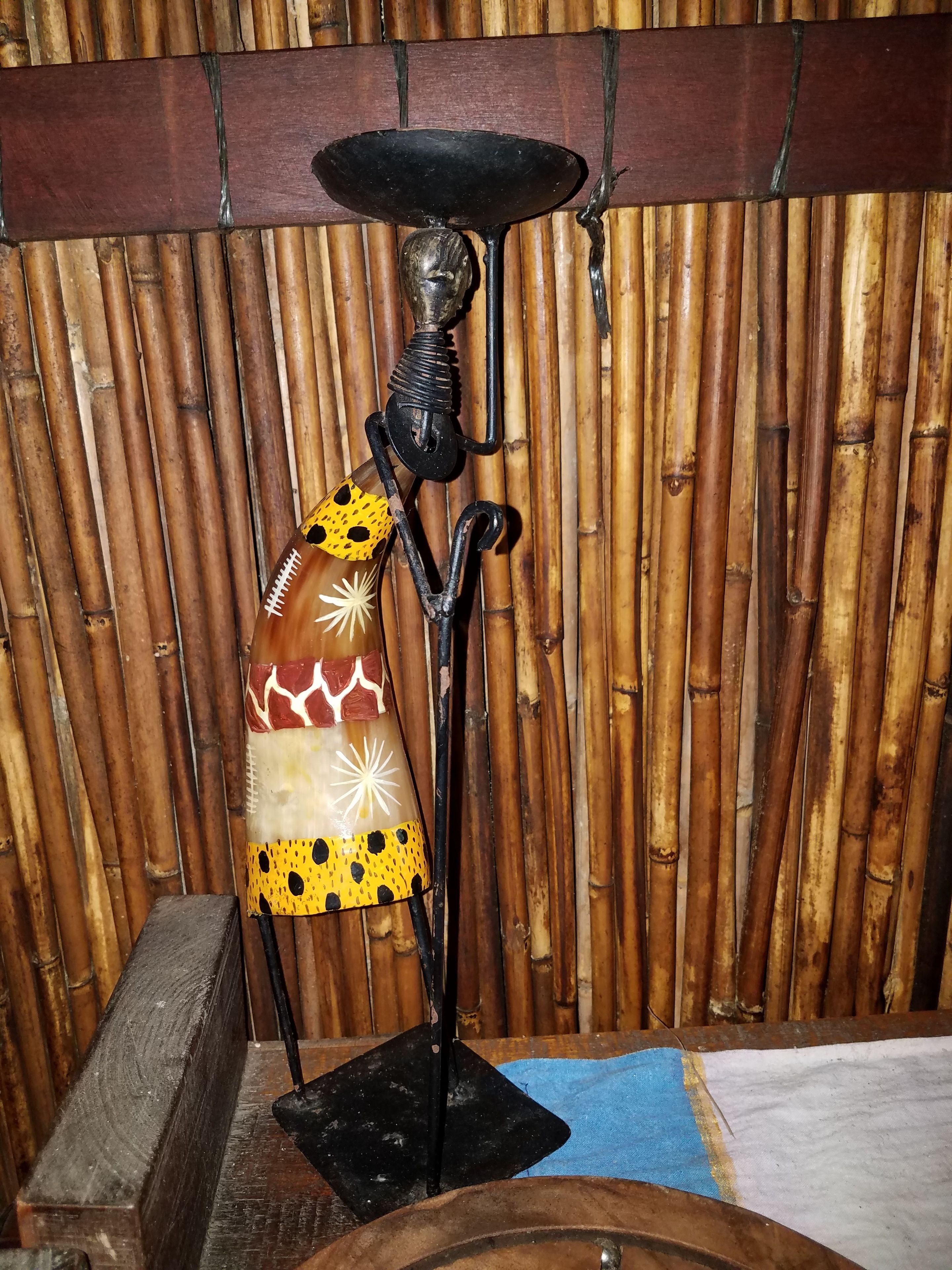 A decorative metal stand with a patterned cloth draped over it, set against a bamboo backdrop.