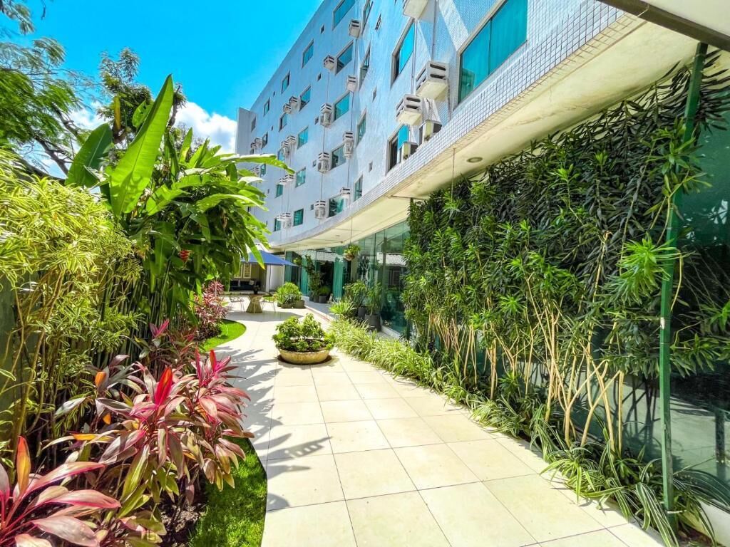 Un bâtiment moderne doté d’une galerie couverte, entouré d’une végétation luxuriante et agrémenté de plantes en pot.
