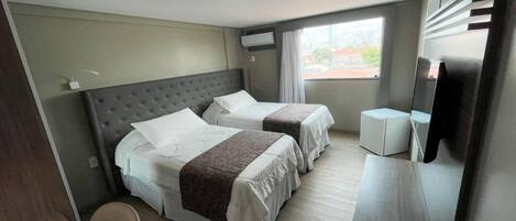 A hotel room with two beds, a desk, and a television.