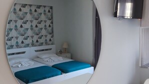 A bedroom with two beds, a TV, and a round mirror. - Sea Vessel (Mylopotamos)