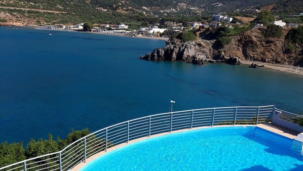 A swimming pool with a stone-tiled deck, a white railing, and a lounge chair. - Sea Vessel (Mylopotamos)