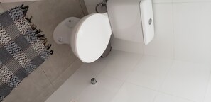 A bathroom with a toilet and patterned rug.