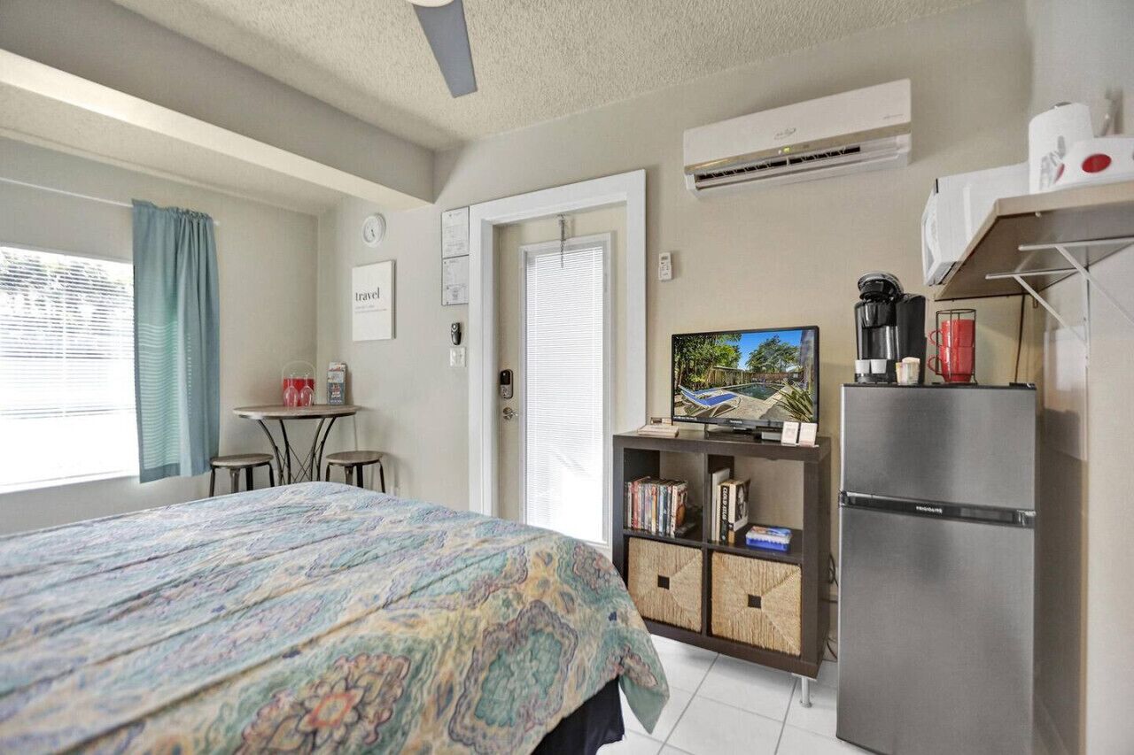 Une chambre à coucher comprenant un lit, une télévision, un réfrigérateur et une petite table avec une chaise.