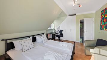 Een slaapkamer met een bed, een bureau, een stoel en een kleurrijk abstract schilderij aan de muur.