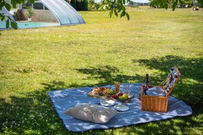 Un pique-nique installé sur un champ herbeux, avec une couverture, de la nourriture et un panier.