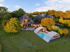 Une grande maison avec une piscine et un espace extérieur couvert.