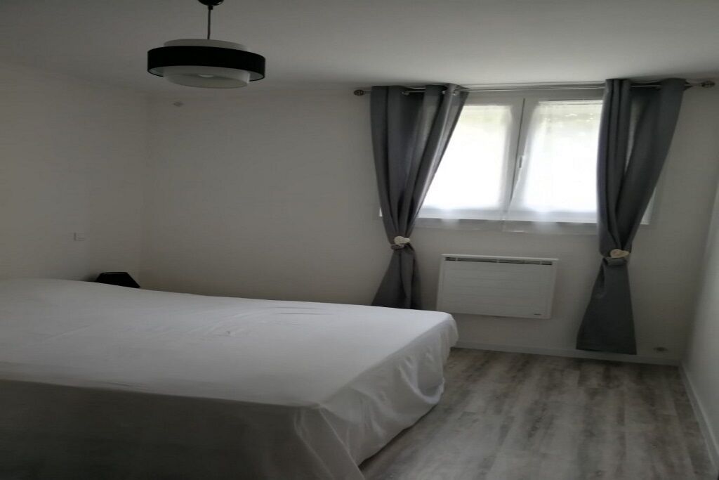 A small, sparsely furnished room with a single bed, a radiator, and a window with curtains.