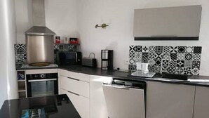 A modern kitchen with white cabinets, a stainless steel range hood, a microwave, a coffee maker, and patterned backsplash tiles. - Ground floor of villa-house, T3 apartment 10 min from Ajaccio with swimming pool. (Afa)