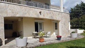 A stone building with a balcony, outdoor seating, and potted plants. - Ground floor of villa-house, T3 apartment 10 min from Ajaccio with swimming pool. (Afa)