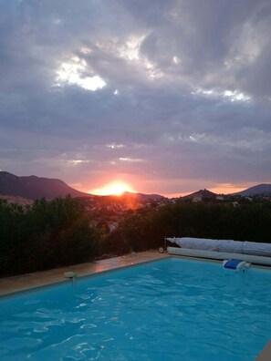Een zwembad met uitzicht op een zonsondergang boven de bergen en een heldere lucht.