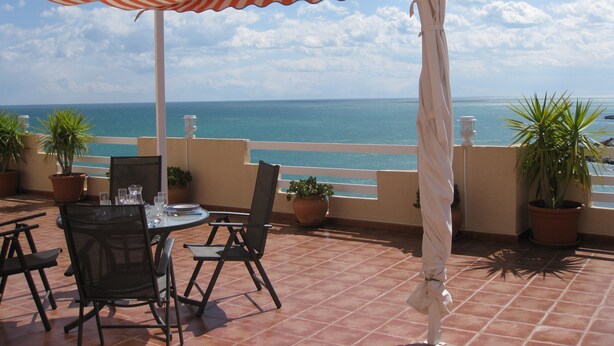 A terrace with a table and chairs, potted plants, and a view of the sea. - panoramic terrace air-conditioned apartment 2 bedrooms 4 pers (Peñíscola)