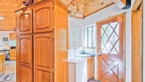 Una cocina con armarios de madera, un refrigerador blanco y una puerta doble con diseño de rombos.
