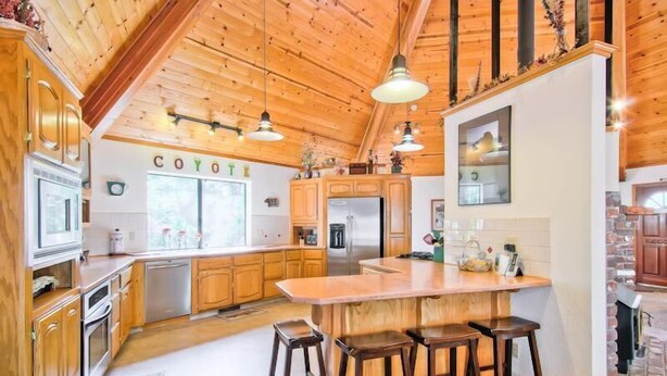 Una cocina amplia con armarios de madera, una isla grande con taburetes y vistas al exterior.