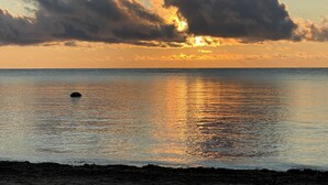 Ein Sonnenuntergang über ruhigem Meer mit der Silhouette einer Wolke.