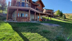 A large, two-story log cabin with a balcony and a covered porch area. - Fantastic view! Arcade, Jacuzzi, Family Friendly Cottage! (Garden City)