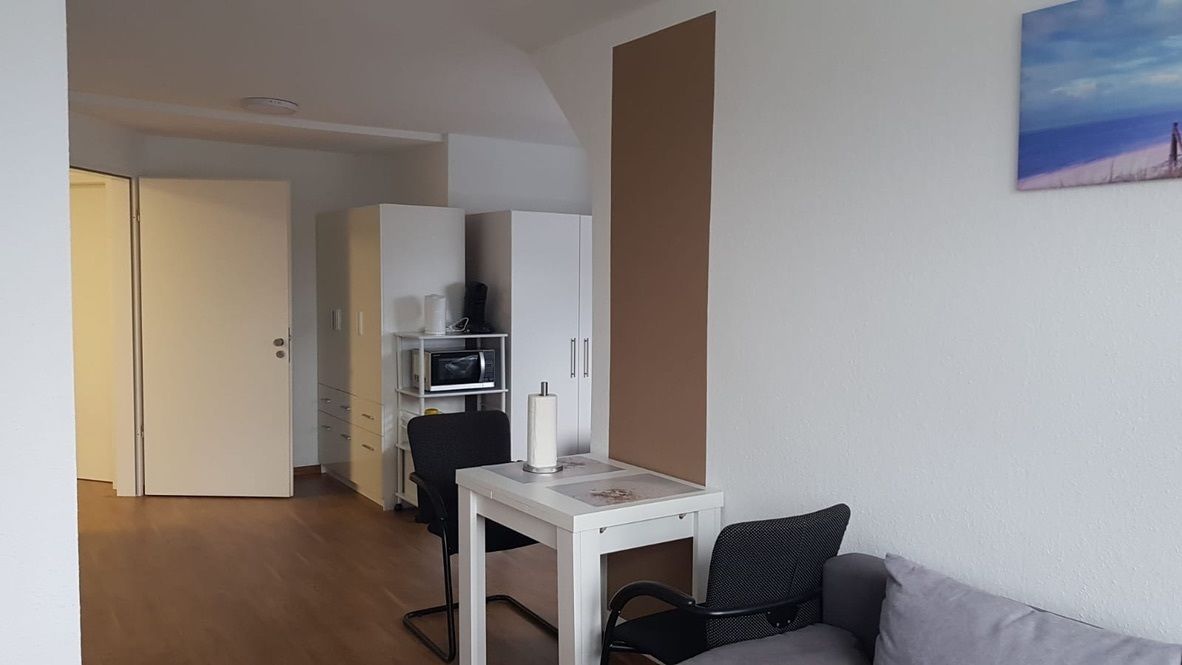 Ein kleiner Wohnbereich mit Küchenzeile, einer Couch und einem Esstisch.
