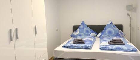 Une chambre à coucher avec un lit, deux oreillers, une table de chevet et une armoire.