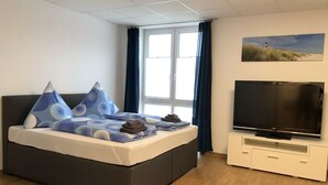 Een slaapkamer met een bed, een televisie en een raam met gordijnen.