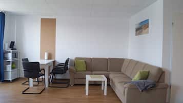 Una sala moderna con un sofá color beige, una mesita blanca y una silla negra.