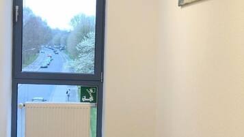 A room with a large window, a radiator, and a painting on the wall.