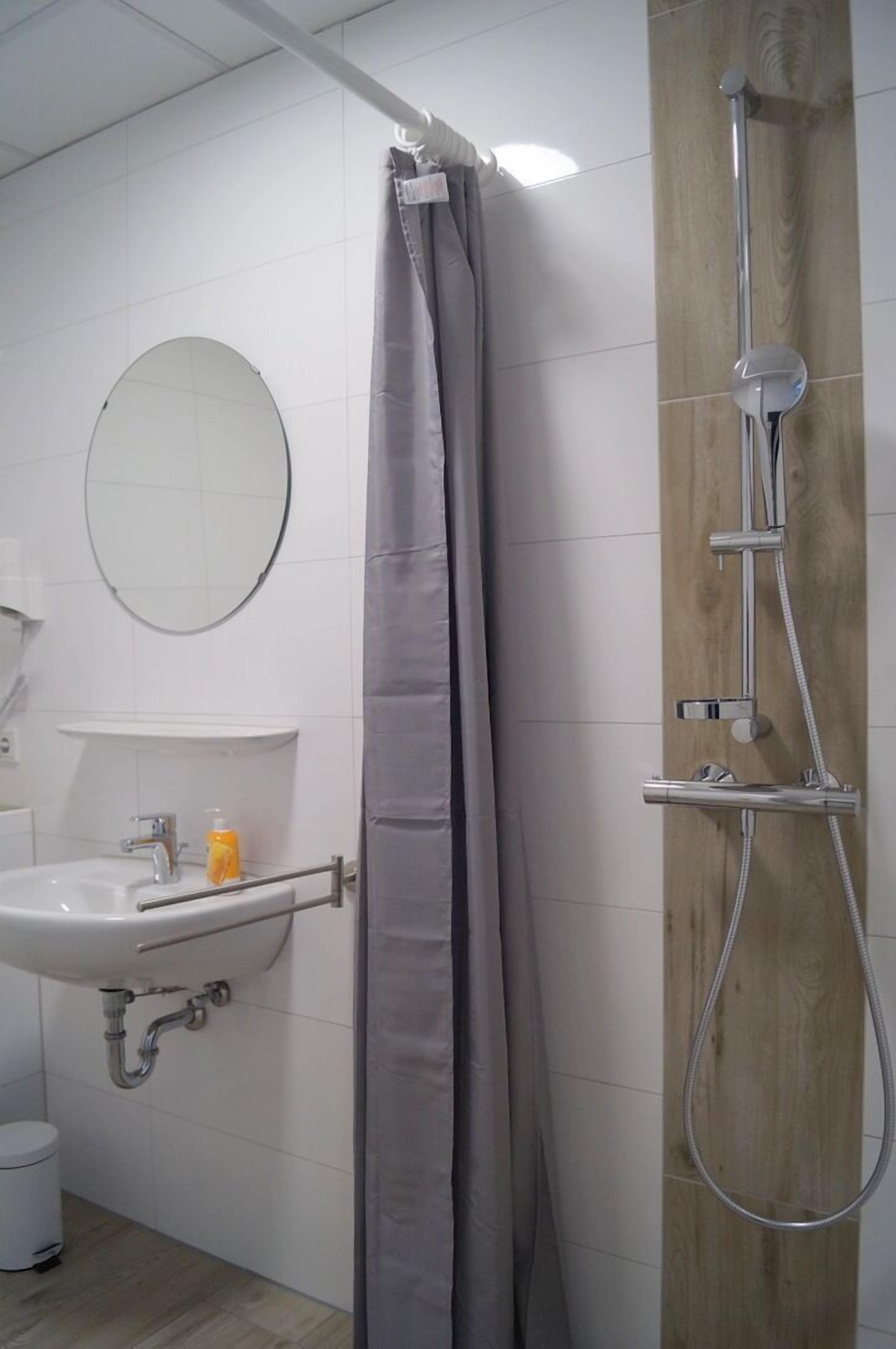 A bathroom with a shower, sink, and mirror.