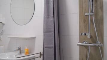 A bathroom with a shower, sink, and mirror.