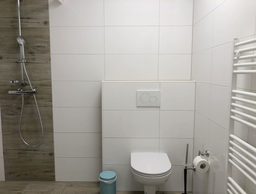 A modern bathroom with a shower, toilet, and a towel rack.