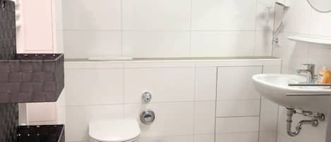 Un baño moderno con inodoro, lavamanos y espejo.