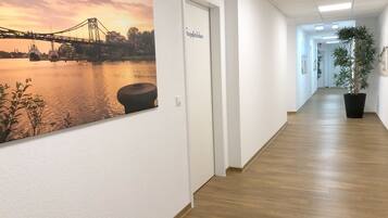 A hallway with a large painting of a bridge over water, a door labeled "Reception," and a potted plant.