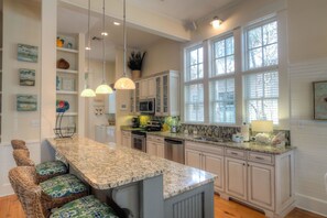 A kitchen with a granite island, white cabinetry, and pendant lighting. - Our Sweet Spot by Exclusive 30A (Santa Rosa Beach)