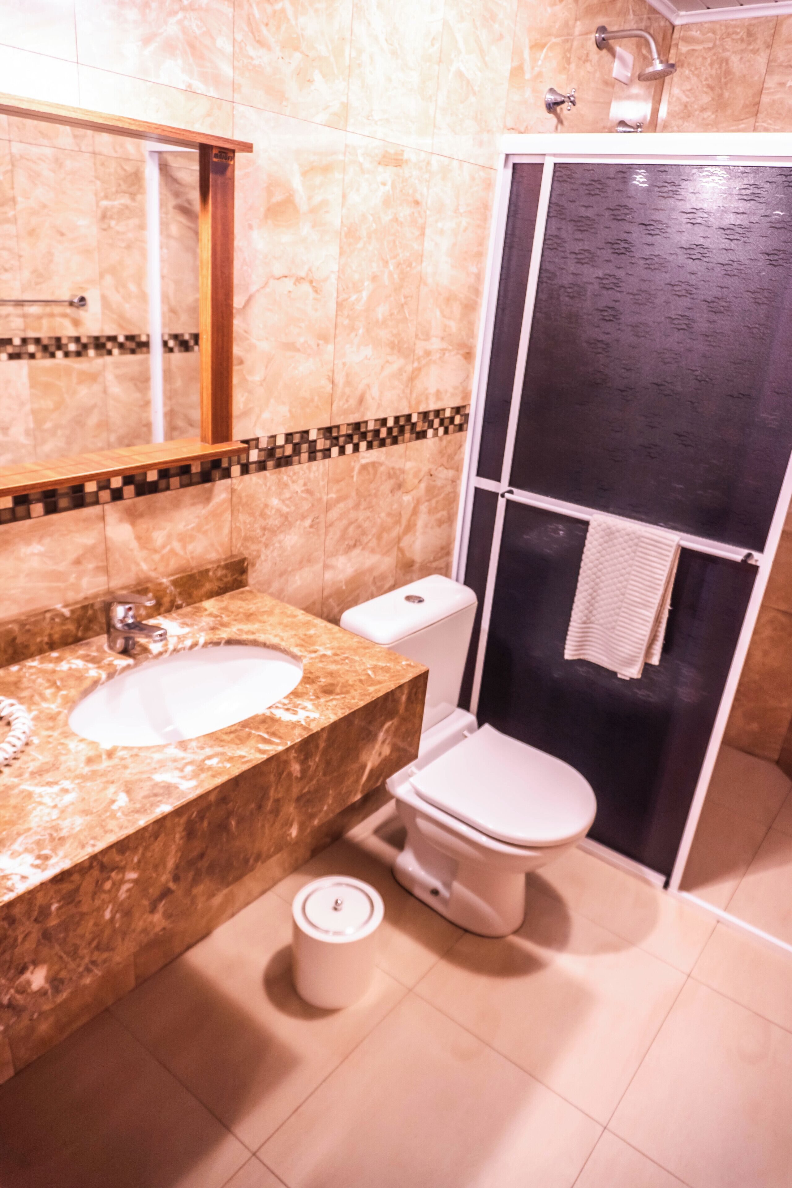 Un baño con lavamanos de mármol, inodoro y cabina de ducha.